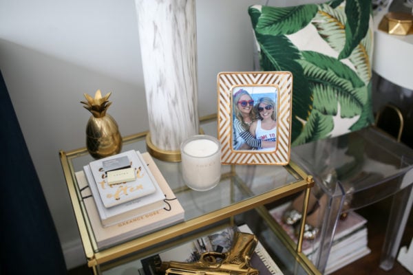 Bows & Sequins living room decor: gold pineapple, palm printed throw pillow, marble lamp, Garance Doré photography book.