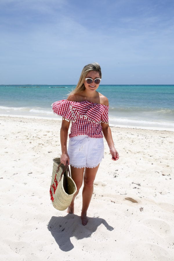 Bows & Sequins, a Chicago-based travel blogger, wearing a red gingham pom pom top with white eyelet shorts in Mexico.