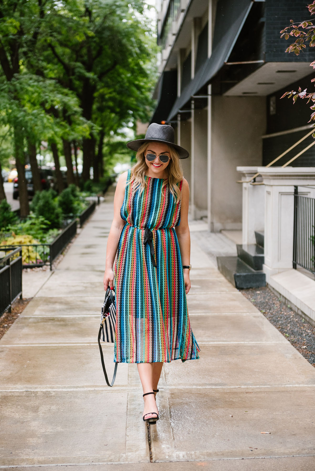 Bows & Sequins wearing an Eva Franco midi dress with black sandals and a Clare V striped bag.