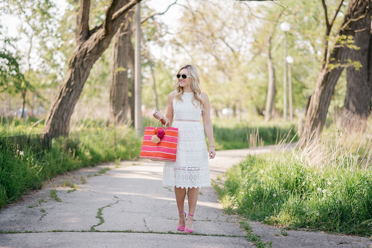 Chicago lifestyle blogger Bows & Sequins wearing a J.O.A. white lace dress and holding a pink and orange striped Mar y Sol straw tote.