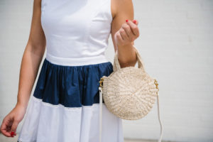 Chicago lifestyle blogger Bows & Sequins wearing a navy striped dress and holding a Clare V Petit Alice straw bag.