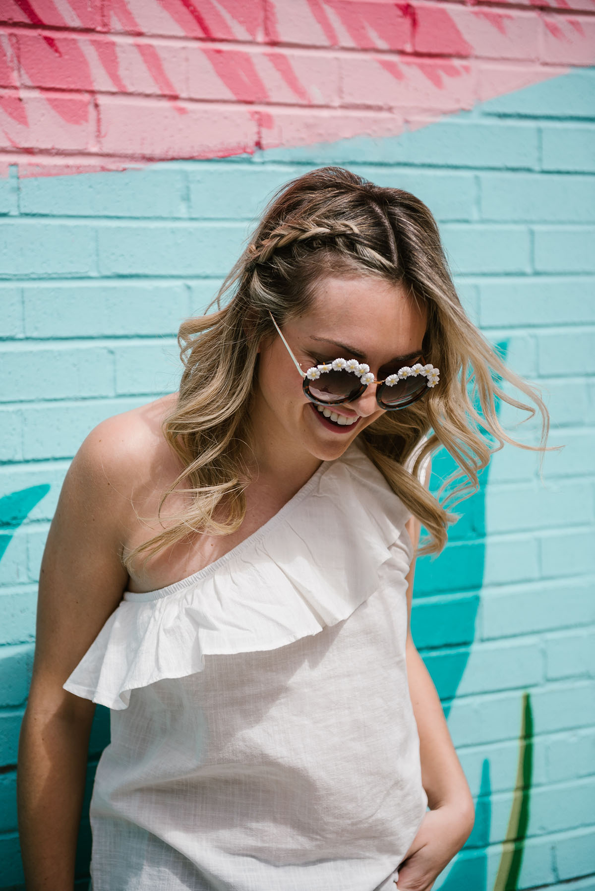 Bows & Sequins wearing a pair of daisy sunglasses and a ruffled one shoulder top with a hair braid for a music festival like Coachella or Lollapalooza.