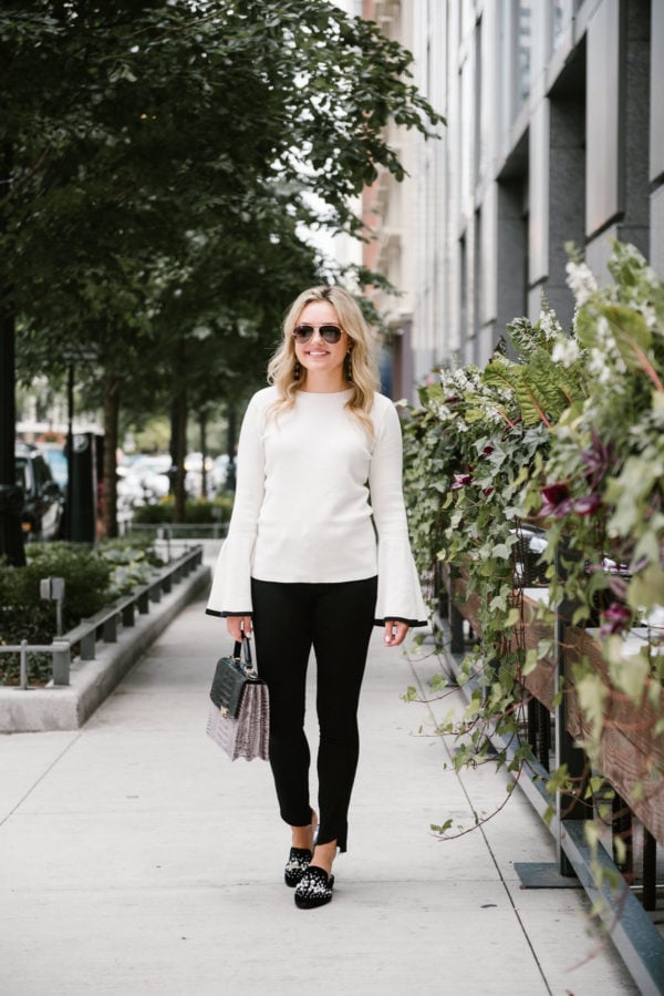 Chicago fashion and lifestyle blogger Bows & Sequins wearing a white Halogen bell sleeve sweater, black Paige jeans, Steve Madden pearl slides, Gucci aviators, and a Brahmin handbag.