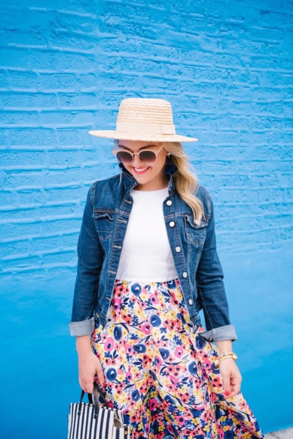 Chicago fashion blogger Bows & Sequins wearing a L Space straw hat and a floral Hutch dress from Anthropologie with a dark wash denim jacket, BaubleBar pom pom earrings, Nordstrom earrings, and a Clare V stripe tote.