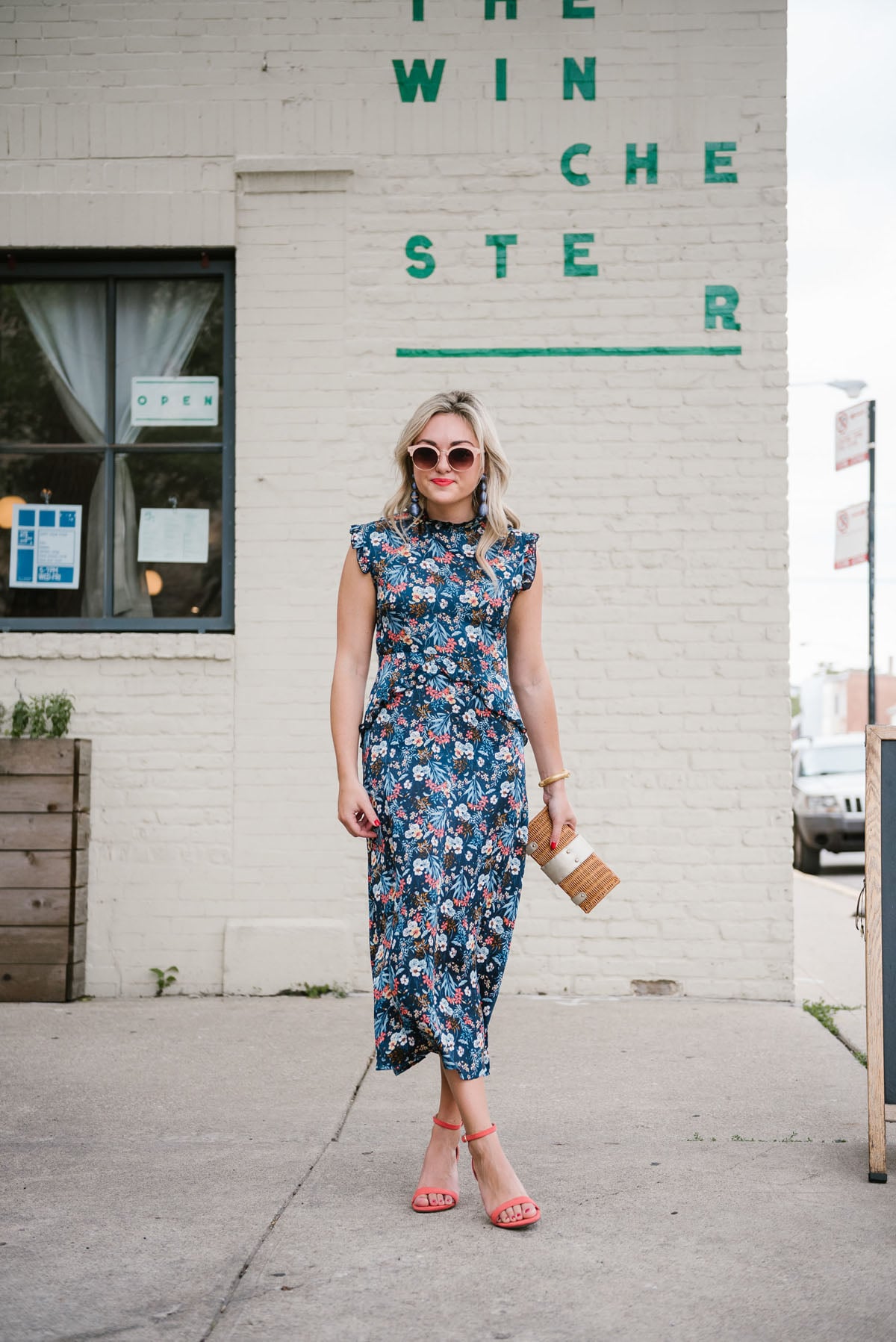 Bows & Sequins wearing a Les Petites silk midi dress with coral Old Navy sandals, blue Bon Bon earrings from Tuckernuck, a Julie Vos cuff, and a wicker clutch outside The Winchester restaurant in Chicago.