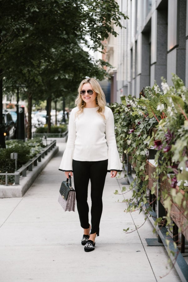 Bows & Sequins wearing a white Halogen bell sleeve sweater, raw hem Paige black denim, and Steve Madden pearl slides.