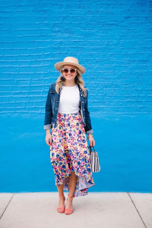 Bows & Sequins wearing a high-low floral dress with coral heels and a straw hat.