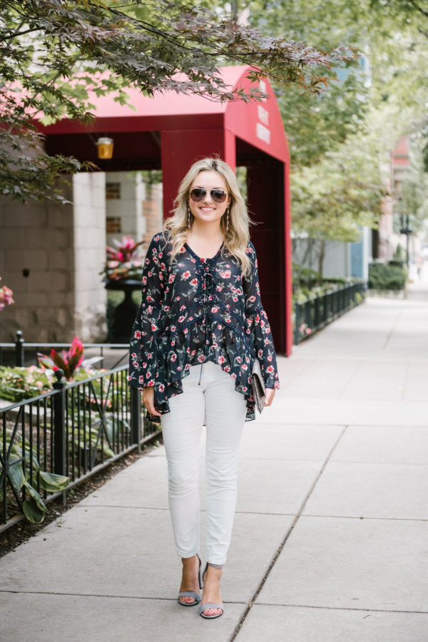 Bows & Sequins wearing white corduroy jeans, a floral blouse, studded ankle strap heels, and Gucci aviators.