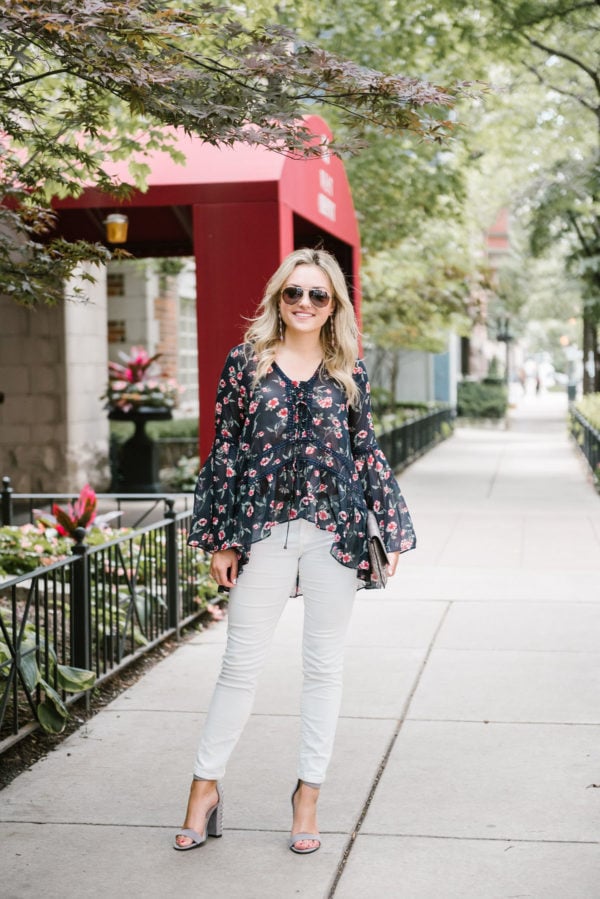 Jessica of Bows & Sequins, a fashion-focused lifestyle blog, wearing Gucci aviator sunglasses, a Moon River tie-neck blouse, white corduroy jeans, and studded heels, holding a metallic clutch.
