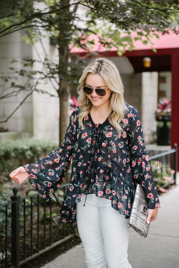 Bows & Sequins wearing a Moon River flare sleeve floral blouse with a metallic silver clutch and Gucci aviators.