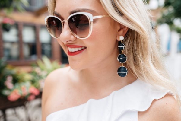 Chicago based fashion and lifestyle blogger, Bows & Sequins, wearing Call It Spring sunglasses and Baublebar navy and white nautical earrings with Dolce & Gabbana red lipstick.