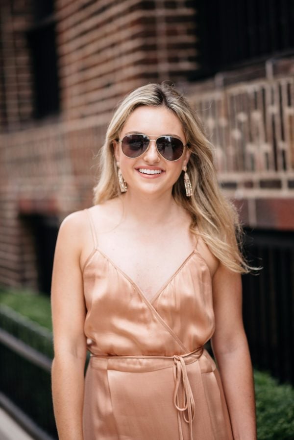 Bows & Sequins styling a metallic Wayf wrap dress with Gucci sunglasses, Charlotte Tilbury nude lipstick, and Baublebar rose gold earrings.