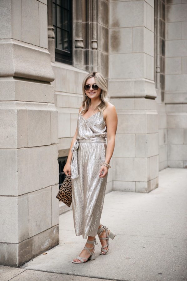 Chicago-based fashion-focused blogger Bows & Sequins wearing a metallic gold Plissé jumpsuit from Nordstrom with a leopard clutch, Gucci aviator sunglasses, grey suede sandals, and pavé bracelets.