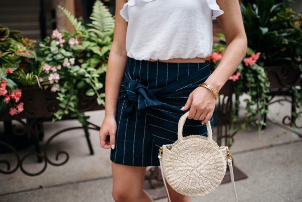 Chicago-based fashion blogger Bows & Sequins wearing a J.O.A. pinstripe tie-front skirt with a Clare V straw tote and Chanel bracelet via Switch.