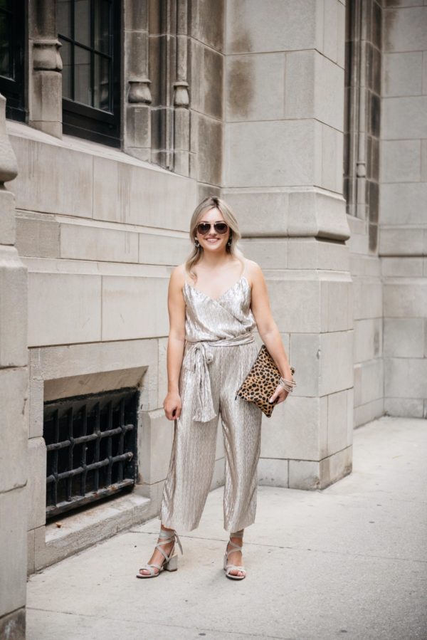 Bows & Sequins wearing a metallic gold tie-waist Nordstrom jumpsuit with Gucci aviators, a leopard print clutch from Clare V, Loren Hope earrings, and grey suede heels.