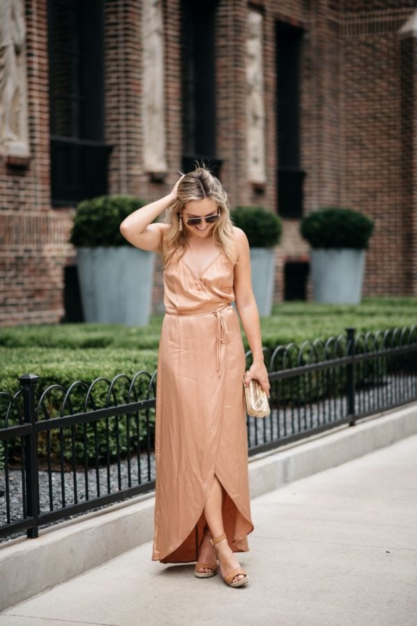 Bows & Sequins styling a Wayf metallic silk dress with gold accessories: a Marc Jacbos pouch, Gucci aviators, and Baublebar rose gold earrings.