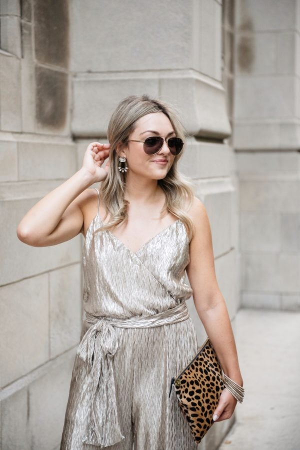 Bows & Sequins styling a metallic gold Plissé jumpsuit from Nordstrom with a Clare V leopard clutch, pavé bangles, Loren Hope earrings, and Gucci sunglasses.