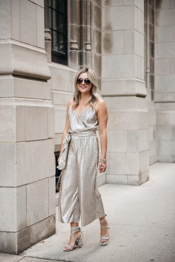 Bows & Sequins wearing a tie-waist gold jumpsuit from Nordstrom with grey suede sandals and pavé bracelets.