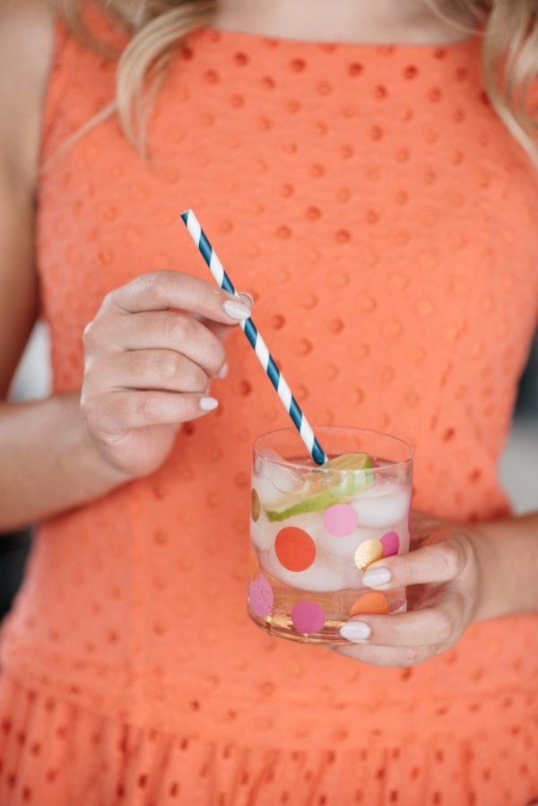 Bows & Sequins holding a polka dot tumbler with a striped straw.
