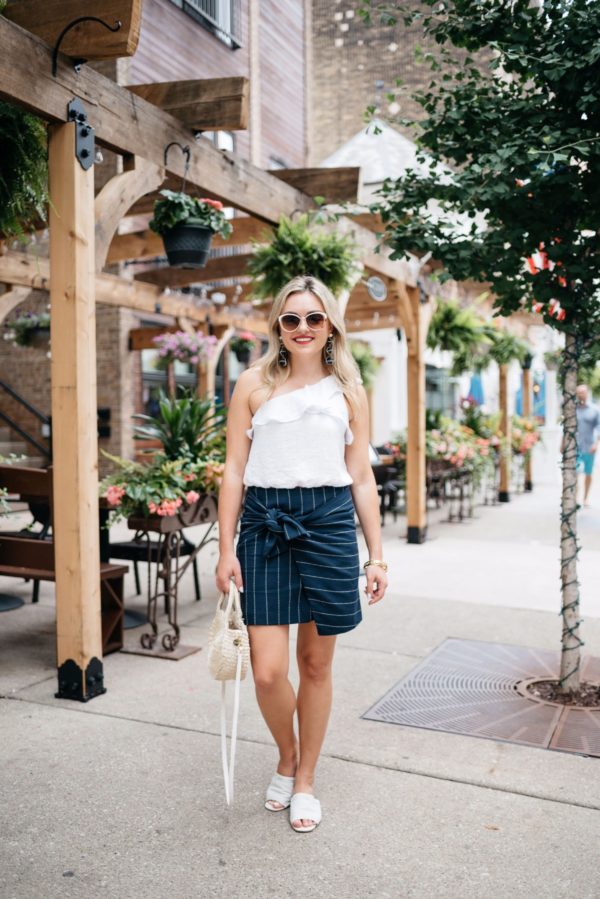 Chicago fashion-focused blogger Bows & Sequins wearing a J.O.A. pinstripe skirt with an ASTR crop top and white leather slides with a Chanel bracelet and Baublebar nautical earrings.