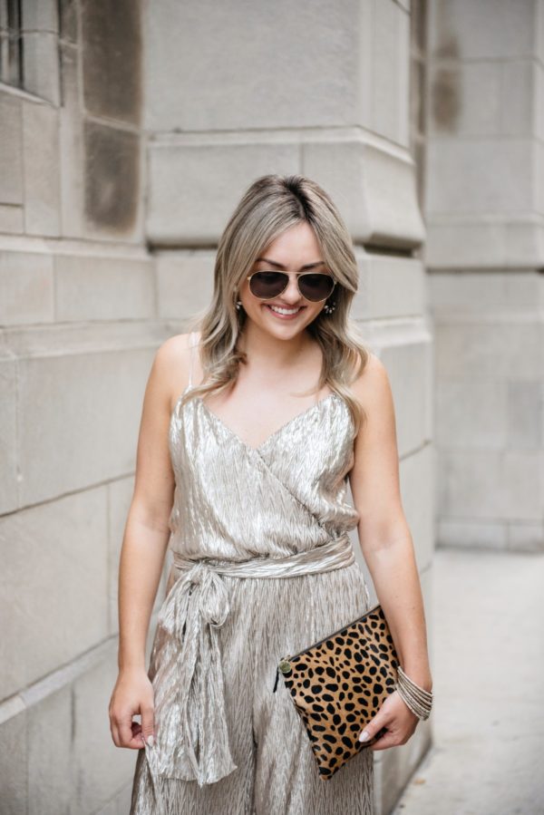 Chicago fashion and lifestyle blogger Bows & Sequins wearing Gucci aviators, a metallic gold jumpsuit from Nordstrom, pavé bangles, Loren Hope earrings, and a Clare V leopard clutch.