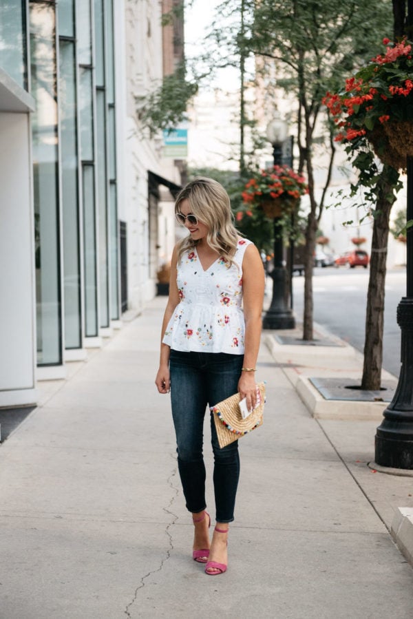 Chicago lifestyle blogger Bows & Sequins wearing a colorful embroidered J.Crew peplum top with Paige jeans, a White Elephant Designs straw pom pom clutch, and Vince Camuto pink ankle strap heels.