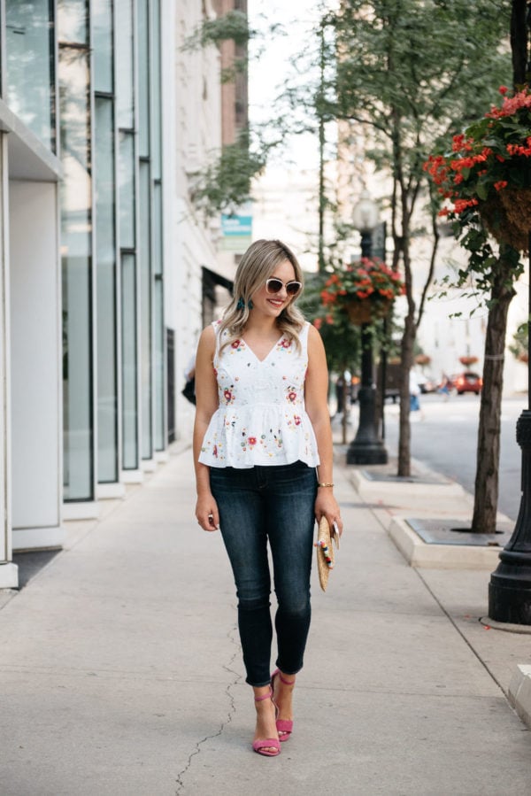 Chicago blogger Bows & Sequins wearing Call It Spring white sunglasses, a J.Crew peplum top, Paige jeans, Vince Camuto pink ankle strap heels, with a White Elephant Designs pom pom straw clutch.