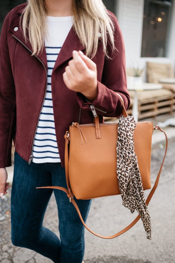Fashion blogger Bows & Sequins sharing fall outfit inspiration: a burgundy suede moto jacket, striped shirt, and an Old Navy leather bag with a leopard scarf.