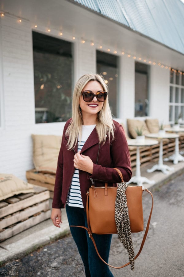 Jessica Sturdy of Bows & Sequins, a Chicago-based fashion-focused blog, wearing Celine sunglasses, a burgundy suede moto jacket, striped shirt, Old Navy Rockstar jeans, and a leather bag with a leopard printed scarf with Bare Minerals matte lipstick in Devious.