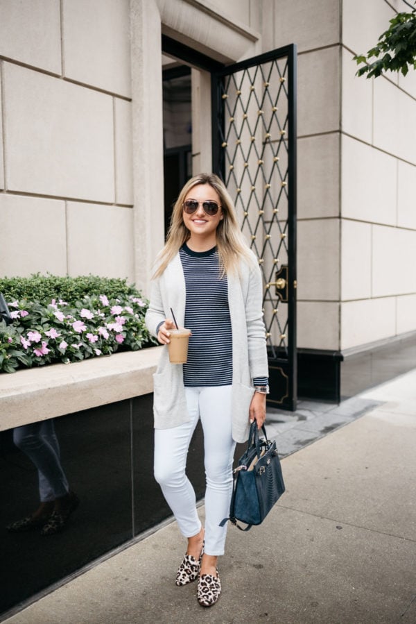 Bows & Sequins, a Chicago-based fashion-focused blogger, wearing an Old Navy cardigan, striped sweater, white jeans, and Kate Spade leopard loafers with a navy tote, David Yurman bracelet, Gucci aviators, and a Coach watch.