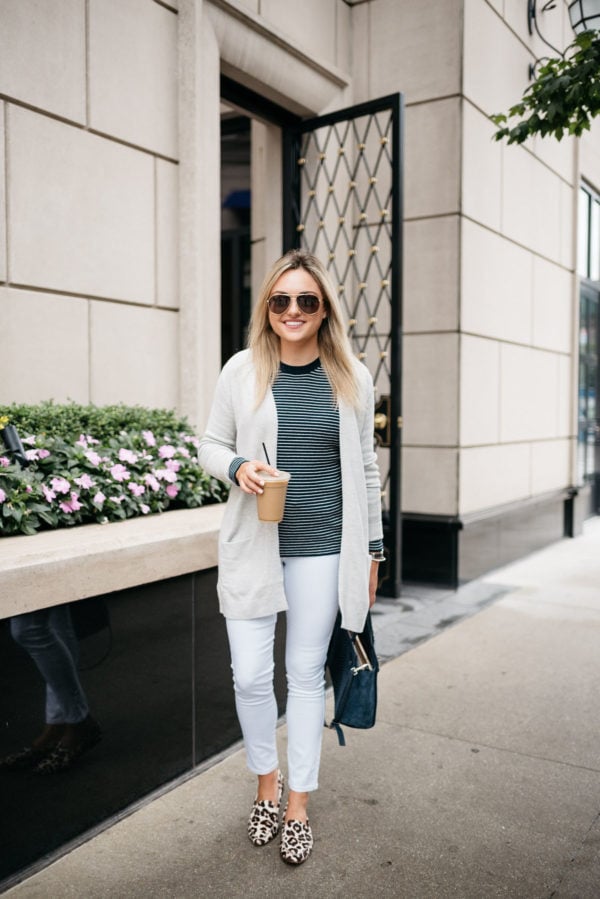 Lifestyle blogger Bows & Sequins wearing Gucci aviators, an Old Navy cardigan, striped sweater, white jeans, Kate Spade leopard loafers, and navy tote at the Waldorf Astoria in Chicago.