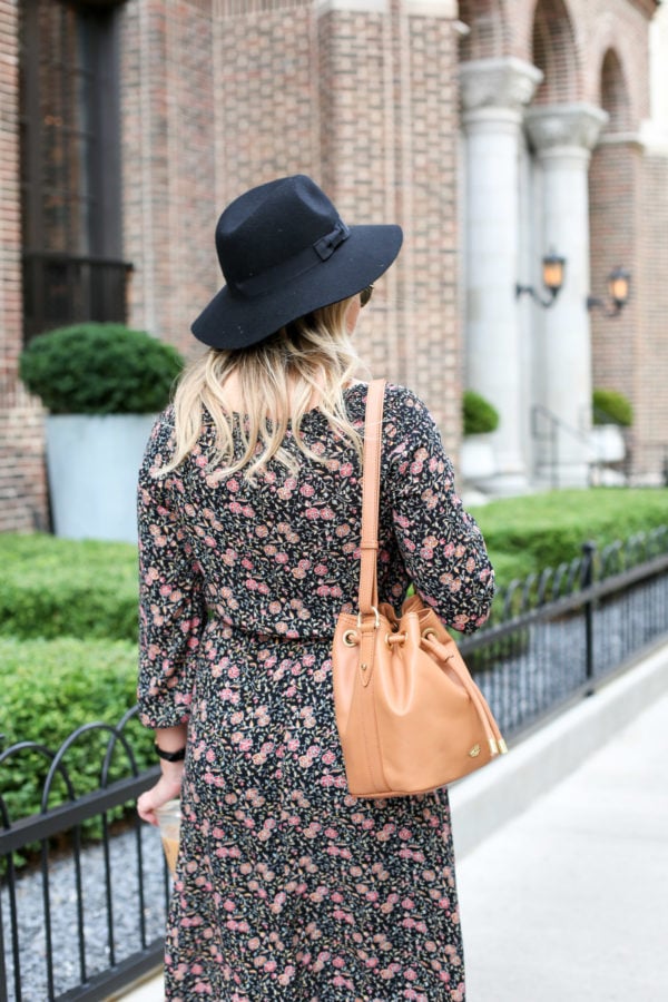 Bows & Sequins wearing a black hat, an Old Navy floral dress, and a Brahmin leather bag.