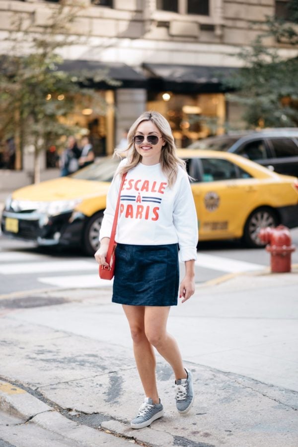 Chicago lifestyle blogger Bows & Sequins wearing Gucci aviators, a French Disorder Paris sweatshirt, and an Old Navy blue suede skirt and Claudie Pierlot gingham sneakers with a Talbots red leather bag.