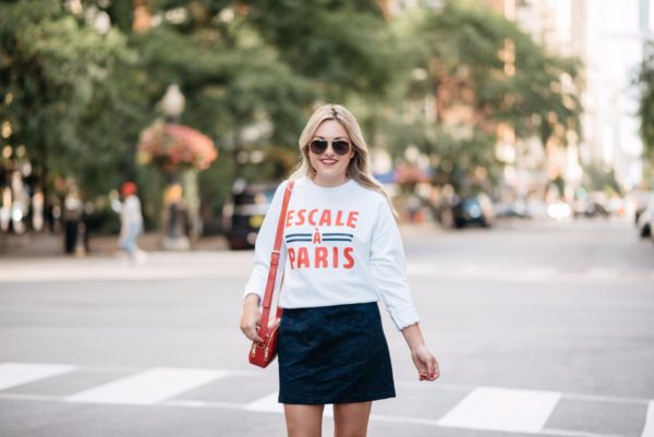 Chicago blogger Bows & Sequins wearing a French Disorder sweatshirt, an Old Navy blue suede skirt, Gucci aviators, and a Talbots red leather bag.
