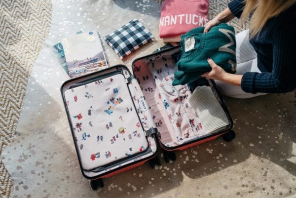 Travel and lifestyle blogger Bows & Sequins packing a pink hard shell suitcase.