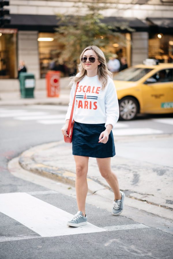 Chicago travel blogger Bows & Sequins wearing Gucci aviators, a French Disorder Paris sweatshirt, and an Old Navy blue suede skirt and Claudie Pierlot gingham sneakers with a Talbots red leather bag.