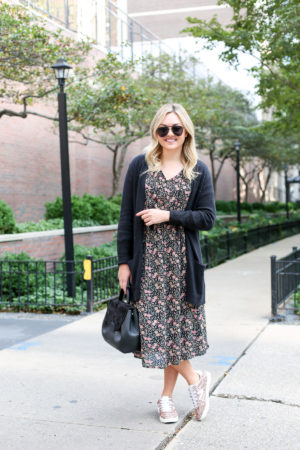 Bows & Sequins wearing a black cardigan, floral midi dress, and pink glitter sneakers with a Polene leather top-handle bag and aviators.