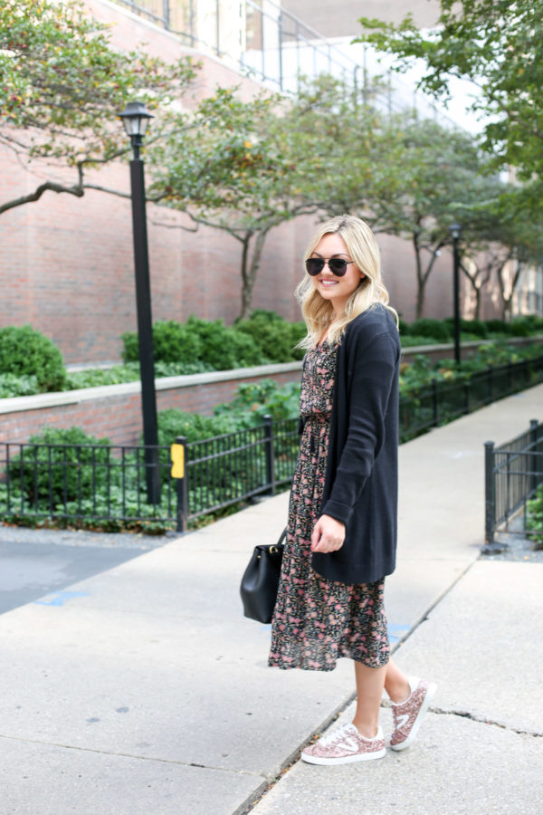 Bows & Sequins wearing matte aviators, a black cardigan, and a floral midi dress with pink glitter sneakers.