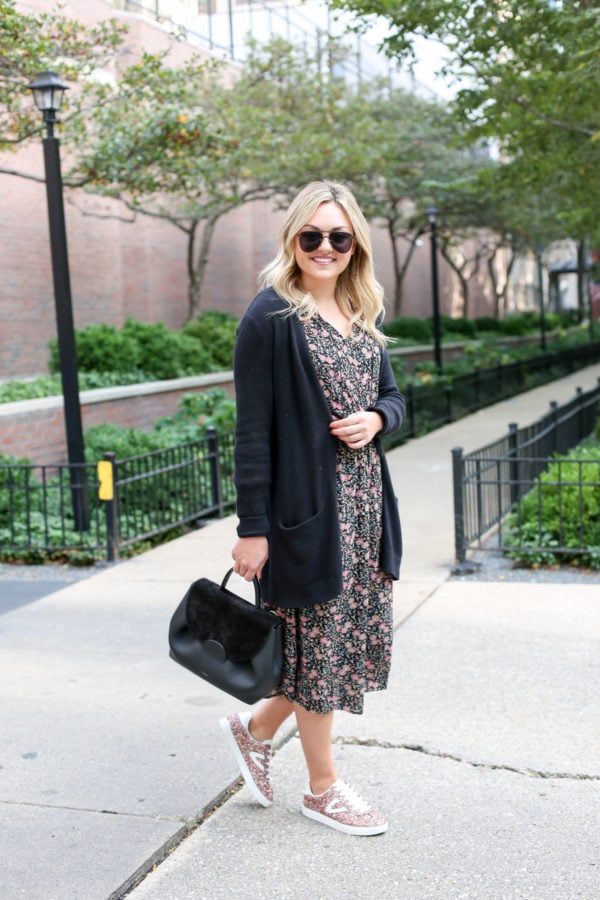 Chicago blogger Bows & Sequins wearing a black cardigan and a floral midi dress with a top-handle Polene bag and pink glitter sneakers.