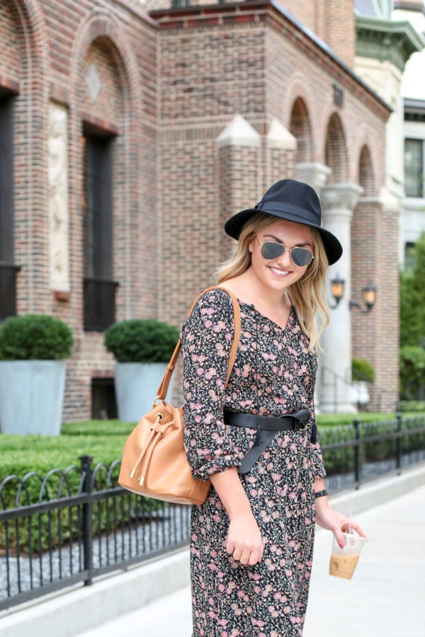 Chicago style blogger Bows & Sequins wearing a black hat, a floral midi dress, a Madewell leather belt, and a Brahmin bucket bag.