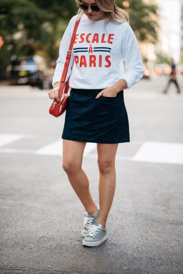 Fashion and travel blogger Bows & Sequins wearing a French Disorder Paris sweatshirt, Old Navy suede skirt, Gucci aviators, Claudie Pierlot gingham sneakers and a Talbots red leather bag.
