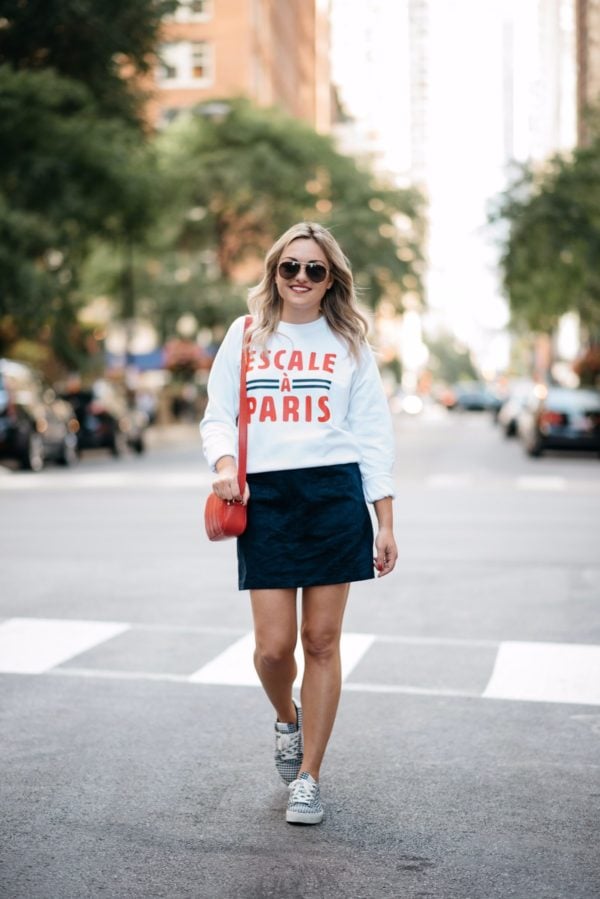Fashion and lifestyle blogger Bows & Sequins wearing a Paris-inspired sweatshirt with Gucci aviators, an Old Navy suede skirt and Claudie Pierlot blue gingham sneakers.