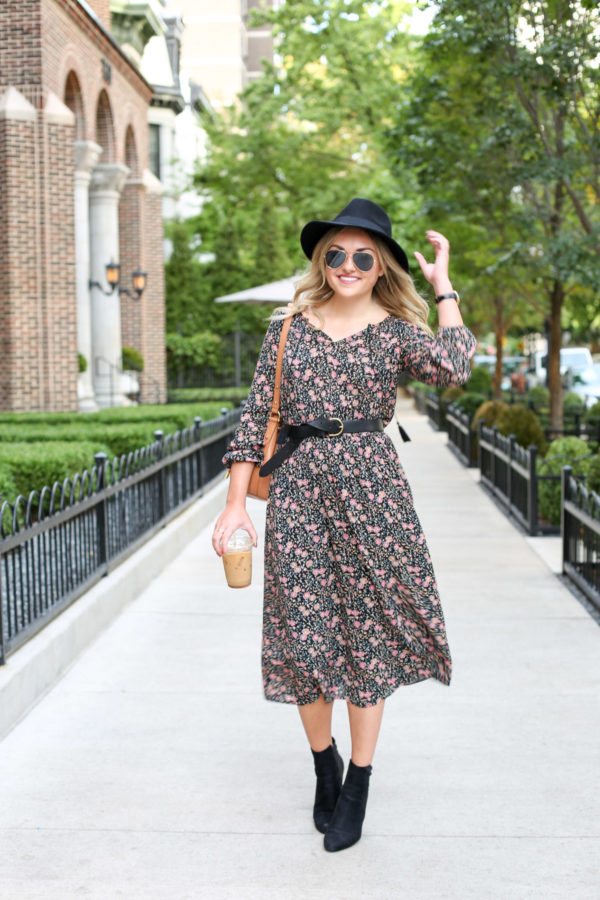 Chicago style blogger Bows & Sequins styling a floral midi dress from Old Navy with a black hat, black leather Madewell belt, and ankle booties.