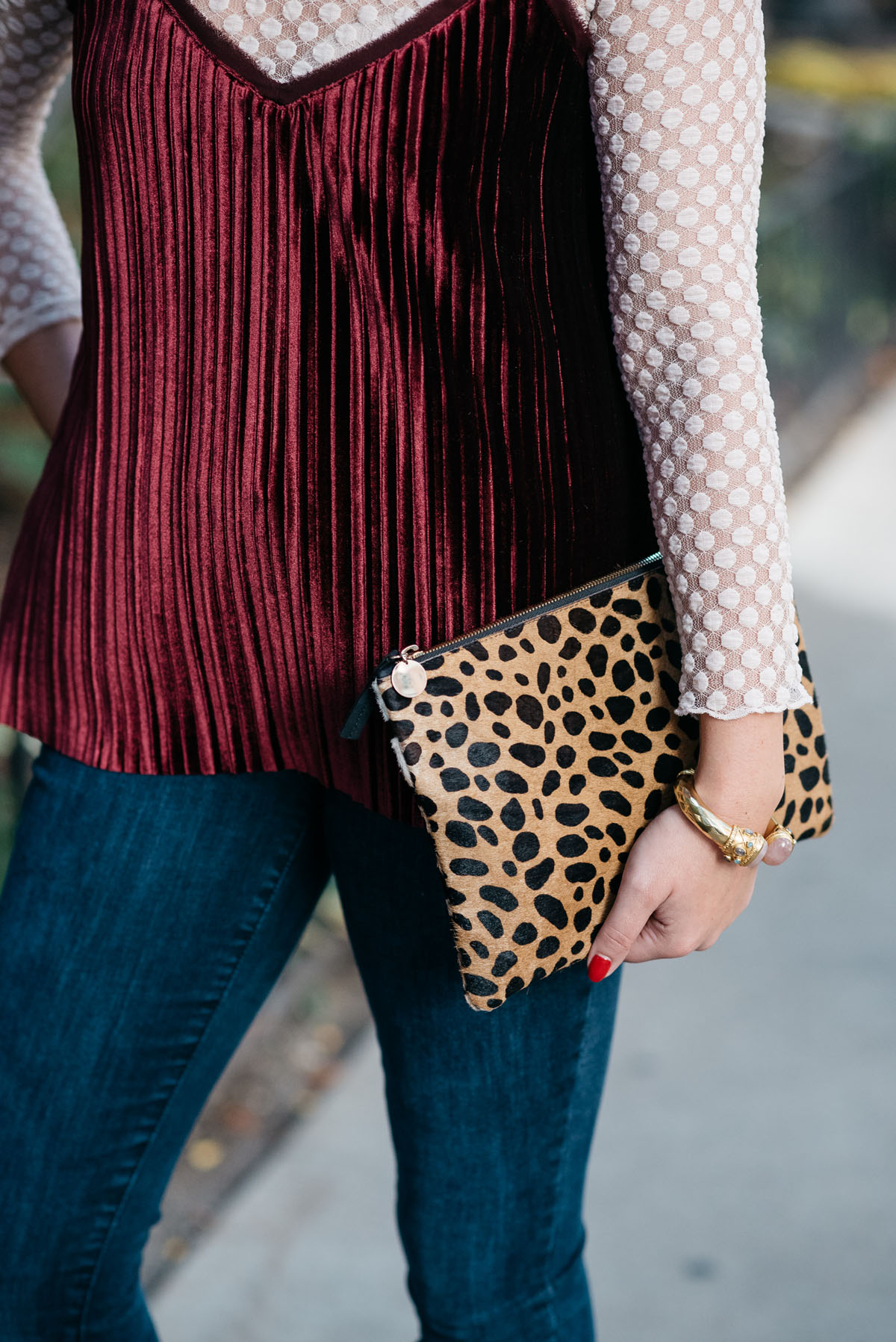 Bows & Sequins wearing a sheer lace turtleneck, a velvet cami, and skinny jeans with a Clare V leopard clutch and a gold cuff.