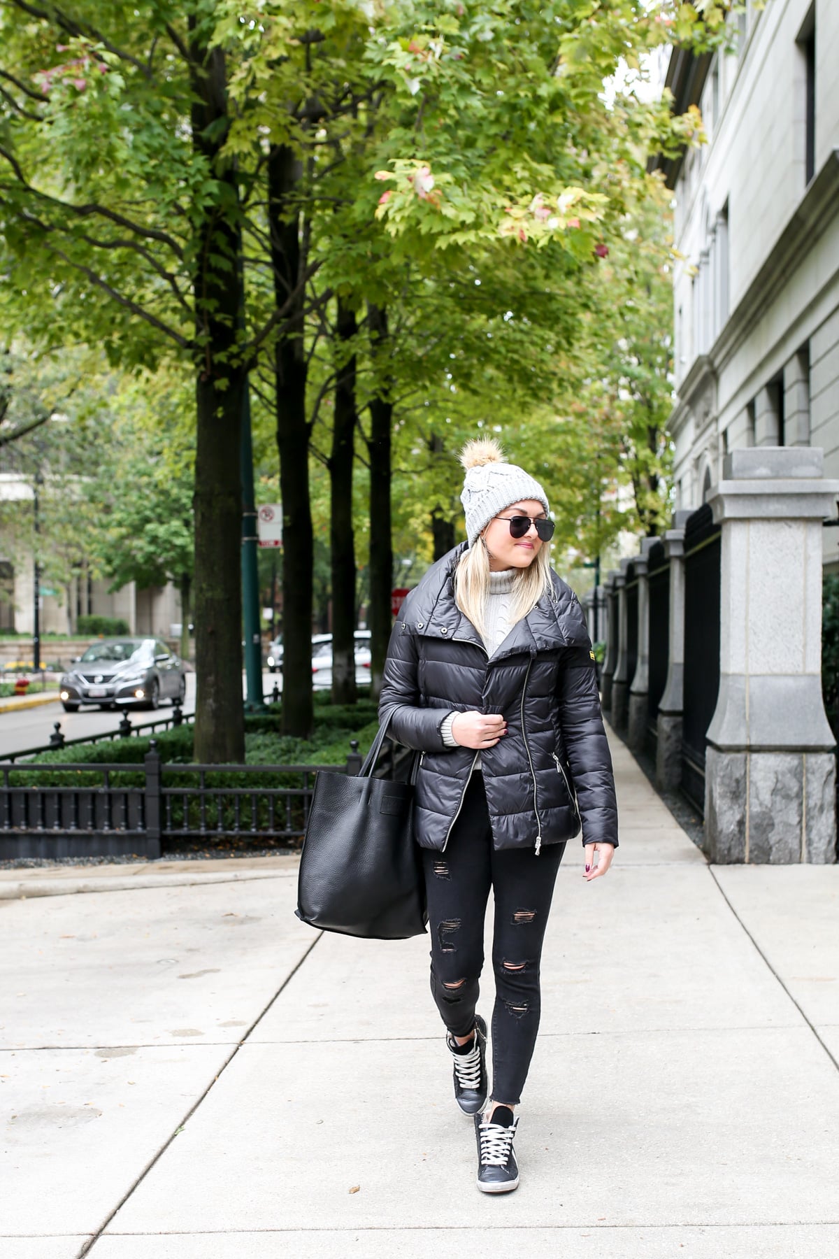 Jessica Sturdy wearing a Barbour quilted jacket with a cable knit sweater, Ashridge beanie, Old Navy black denim, and Kim & Zozi glitter sneakers with a black leather tote.