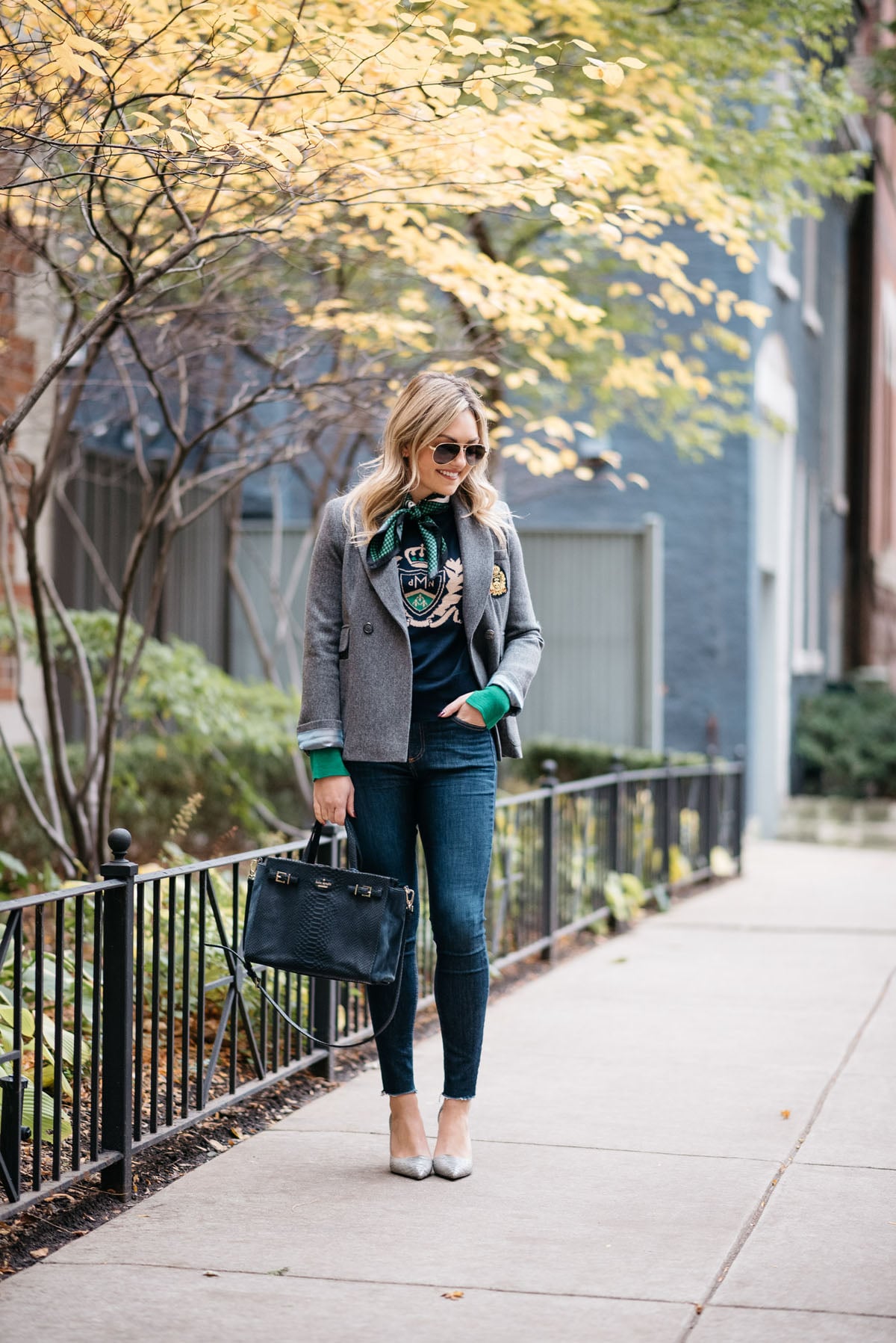 Jessica Rose Sturdy wearing Gucci aviators, a MDN silk neck scarf, MDN grey blazer, Rag & Bone raw hem skinny jeans, and Michael Kors textured pumps with a navy Kate Spade tote.