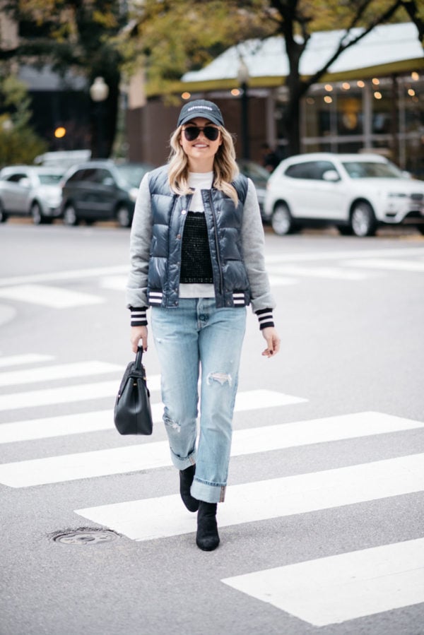 Fashion-focused blogger Jessica Rose Sturdy wearing a baseball cap, a Veronica Beard puffer bomber jacket, an Endless Rose layered tee and crochet tank, Levi 501 Jeans, Steve Madden lucite booties, and a Polene Paris top-handle bag.