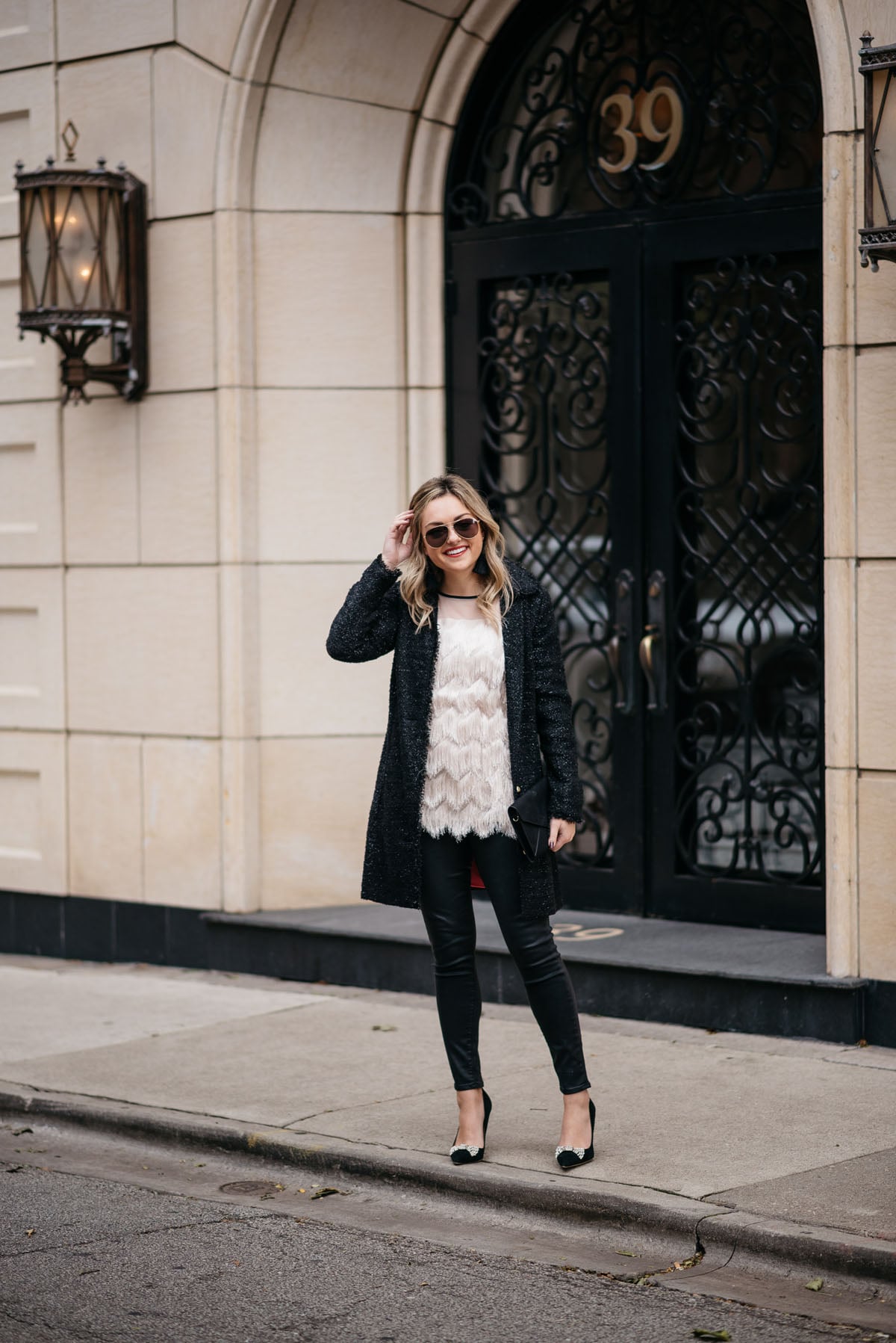 Jessica Sturdy wearing a Sail to Sable sparkly tweed coat, fringe tunic tank, Express waxed black denim, Kate Spade suede bow pumps, and Gucci aviators with an Old Navy embellished clutch.