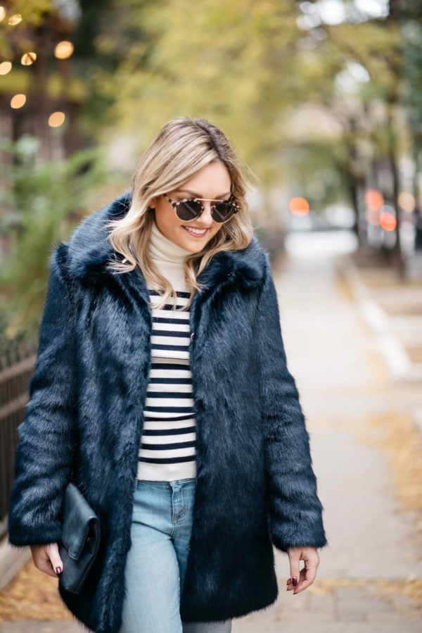Fashion and lifestyle blogger Jessica Sturdy of Bows & Sequins wearing Illesteva sunglasses, an MDN striped turtleneck, Miranda Dunn London faux fur coat and an Azalea Jack foldover clutch.