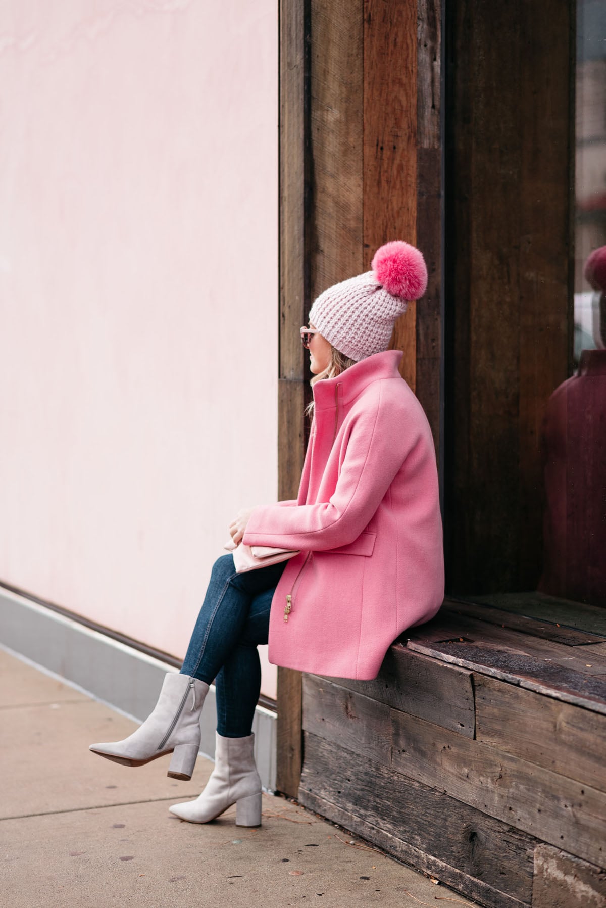 Jessica Sturdy wearing a Kyi Kyi pink pom pom hat, a J.Crew winter coat, Rag & Bone jeans, and Linea Paolo suede ankle booties via Nordstrom.